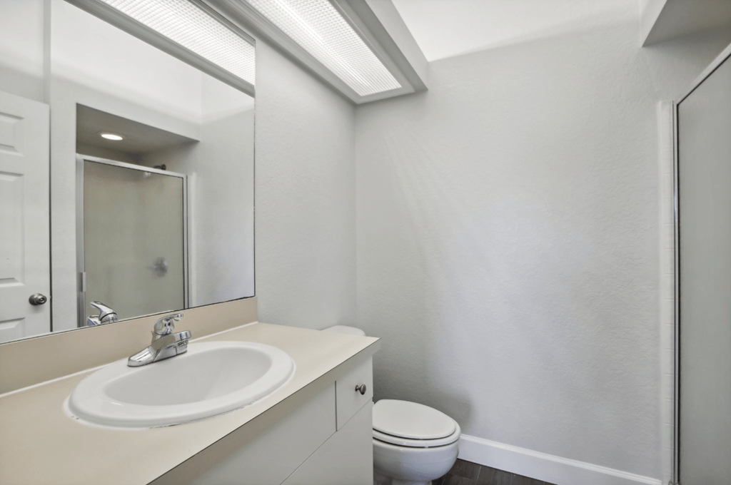 A white sink with a silver faucet is on a countertop in a bathroom.
